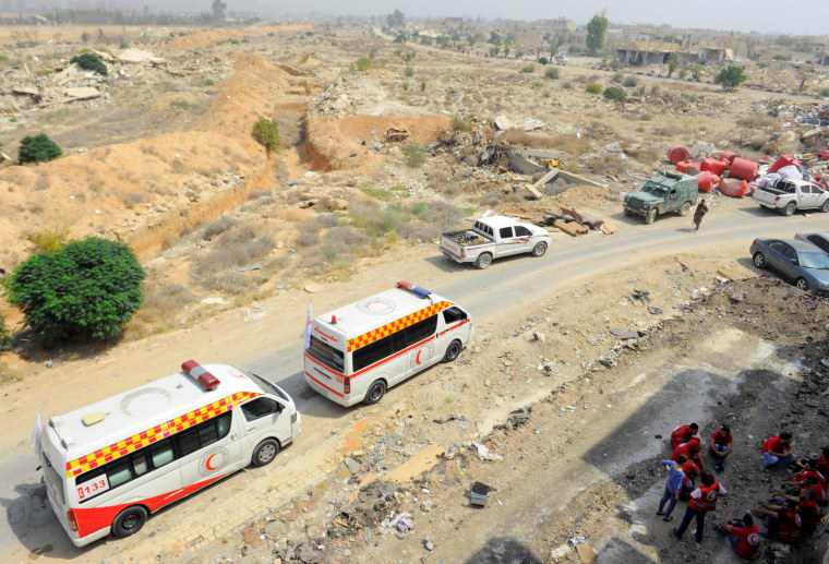 Image: A Syrian Arab Red Crescent convoy waits at the entrance of the besieged Damascus suburb of Daraya