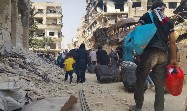 Image: Syrian citizens carry their belonging as they prepare to evacuate from Daraya