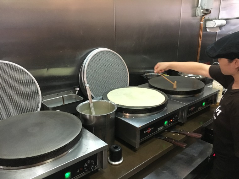 An employee at T-Swirl crepe making one of their signature servings.