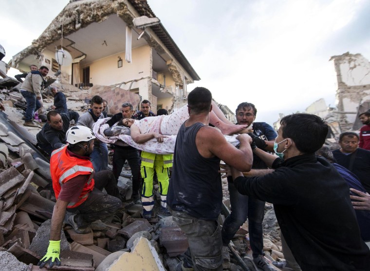 Image: A rescued woman is carried away on a stretcher following an earthquake in Amatrice, Italy