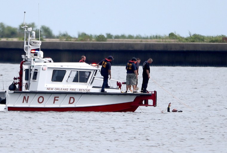 A diver in the water signals to a New Orleans Fire Department boat while searching for the wreckage Sunday, Aug. 28, 2016, near the Seabrook Bridge after a plane crashed into Lake Pontchartrain Saturday night near Lakefront Airport in New Orleans.