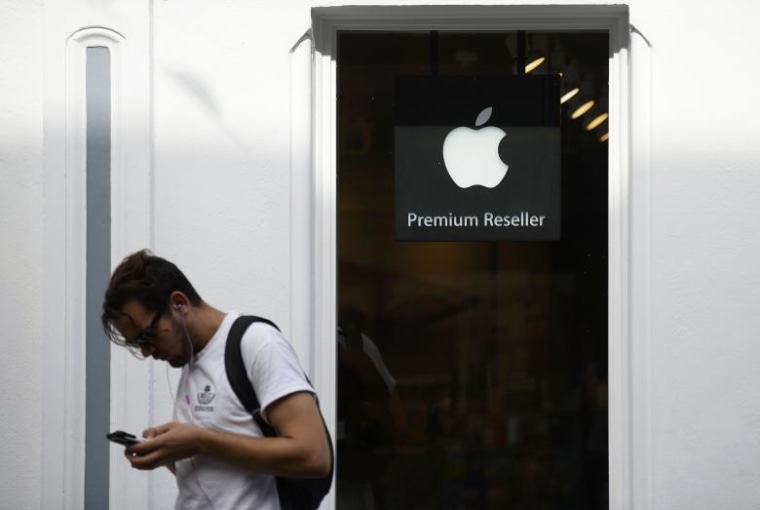 A man looks at his phone as he walks past an authorised apple reseller store in Galway