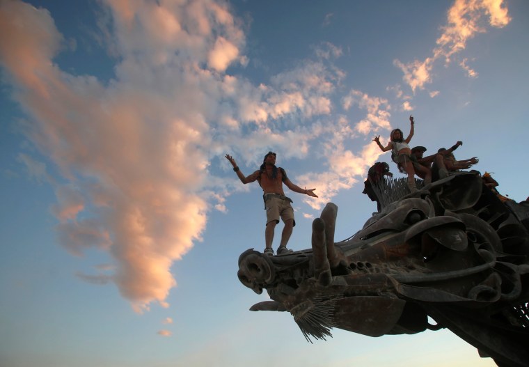 Image: Participants dance and climb on an art installation as approximately 70,000 people from all over the world gather for the 30th annual Burning Man arts and music festival in the Black Rock Desert of Nevada, U.S.