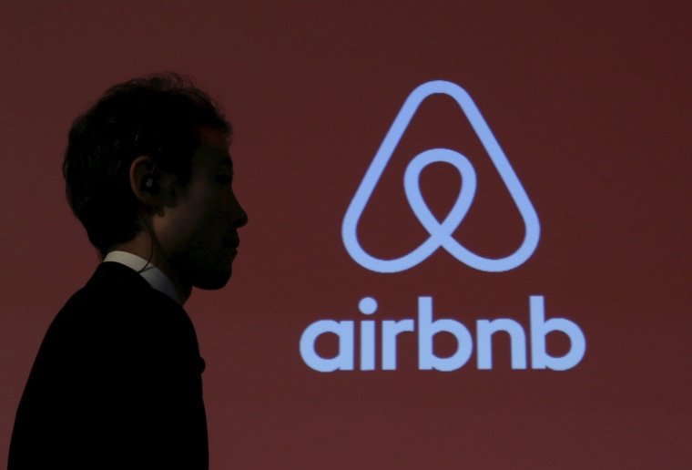 Image: A man walks past a logo of Airbnb after a news conference in Tokyo