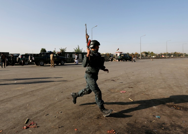 Image: An Afghan policeman arrives at the site of a suicide attack in Kabul