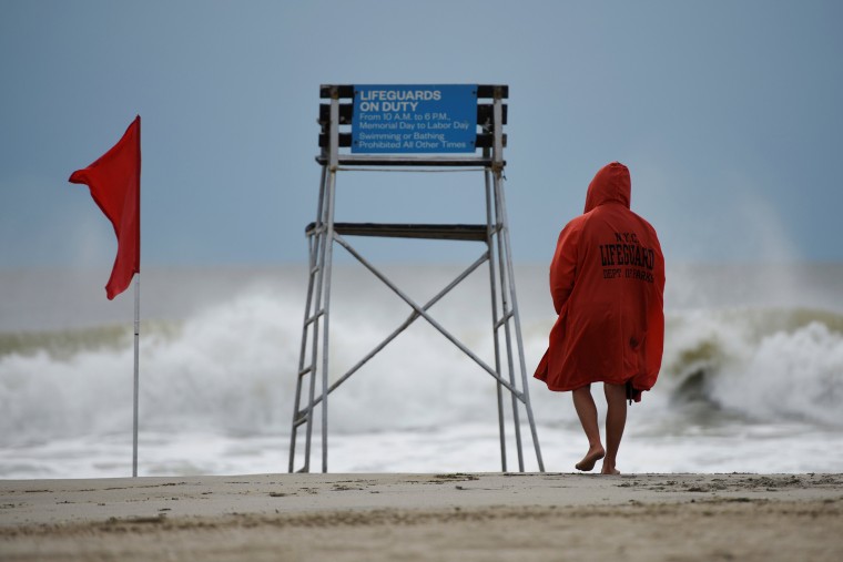 Image: A lifeguard surveys the water where surfers took advantage of the waves at Rockaway Beach in Queens
