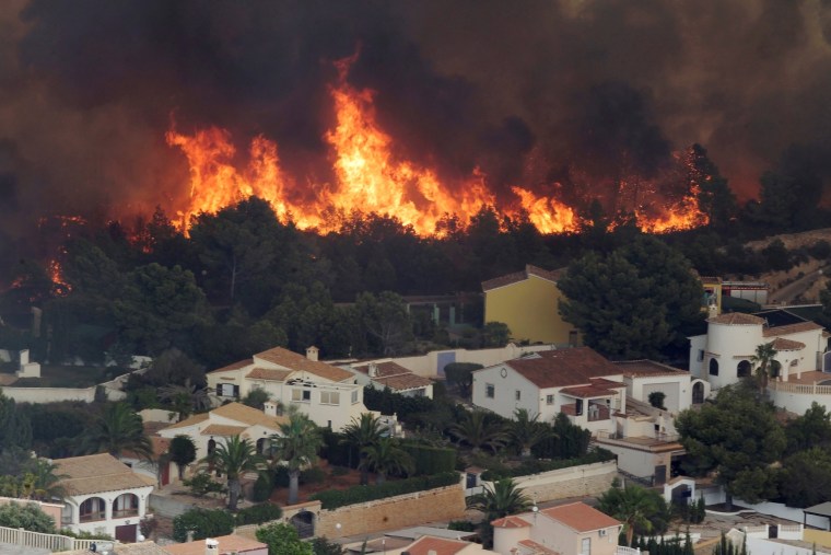 Image: Flames of a wildfire engulf a hillside next to houses in Benitatxell near Alicante