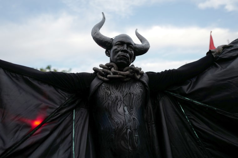 Image: A man dressed as the \"Bat King\" walks down the street as he takes part in J'Ouvert in Brooklyn