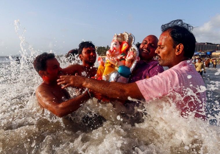 Image: Devotees carry an idol of the Hindu god Ganesh, the deity of prosperity, into the Arabian Sea on the second day of Ganesh Chaturthi festival in in Mumbai