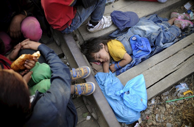 Image: Rashida, part of a new group of immigrants, sleeps as they wait at border line of Macedonia and Greece to enter into Macedonia near Gevgelija railway station