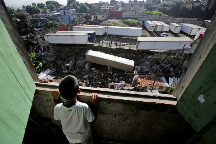 Image: Child looks at the site where a landslide took place causing a trailer to fall on top of homes causing several casualties in Villanueva