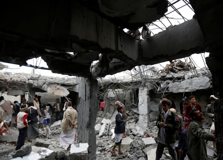 Image: People gather at a building destroyed by Saudi-led air strikes in the northwestern city of Amran, Yemen