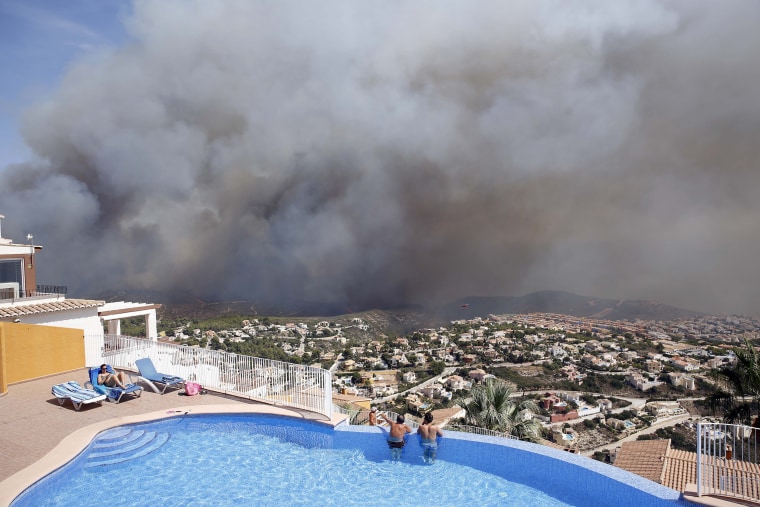 Image: Two men look at a wildfire from a swimming pool