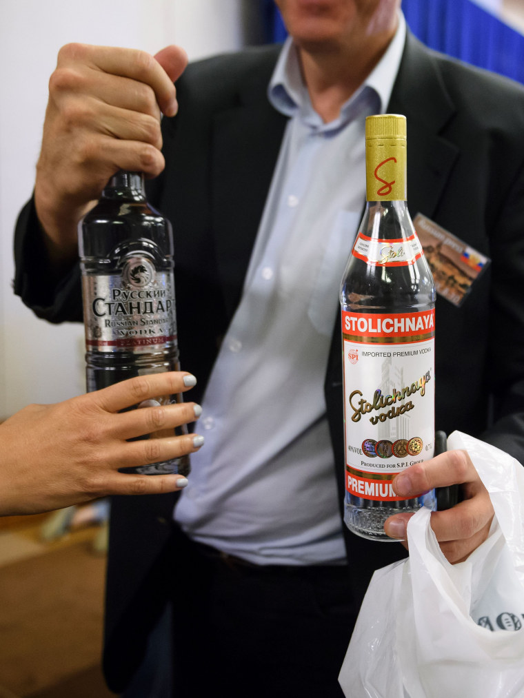 Image: A reporter holds vodka delivered to waiting journalists by Russia's foreign minister Lavov after meetings went late into the evening.