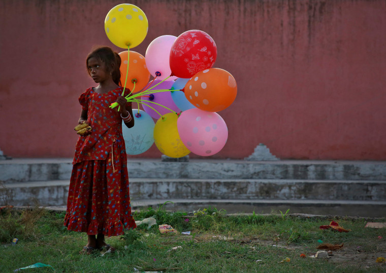 Image: A young girl sells balloons by the Yamuna River as devotees carrying idols of the Hindu god Ganesh, the deity of prosperity, immerse the idol on the last day of the ten-day-long Ganesh Chaturthi festival in Delhi