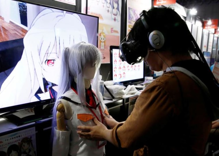 A man touches a mannequin as he tries out a M2 Co.Ltd's \"E-mote\" system as the monitor shows the image from the VR device at Tokyo Game Show 2016 in Chiba