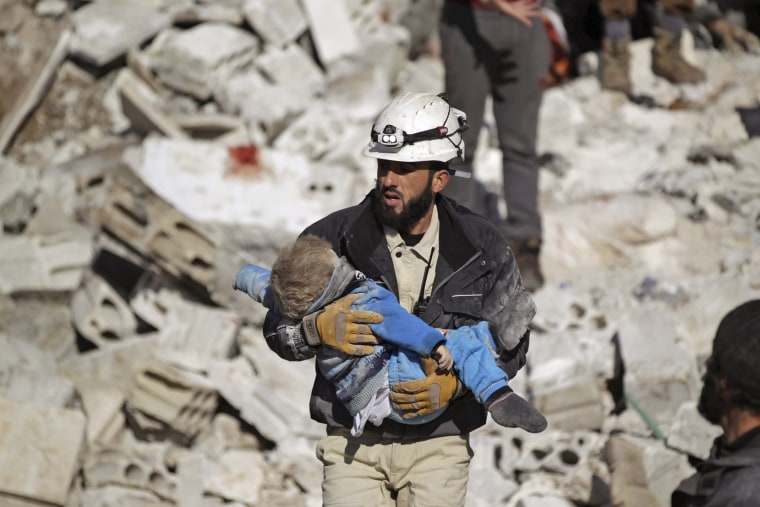 Image: A civil defence member carries a dead child in a site hit by what activists said were airstrikes carried out by the Russian air force in the rebel-controlled area of Maaret al-Numan town in Idlib province, Syria