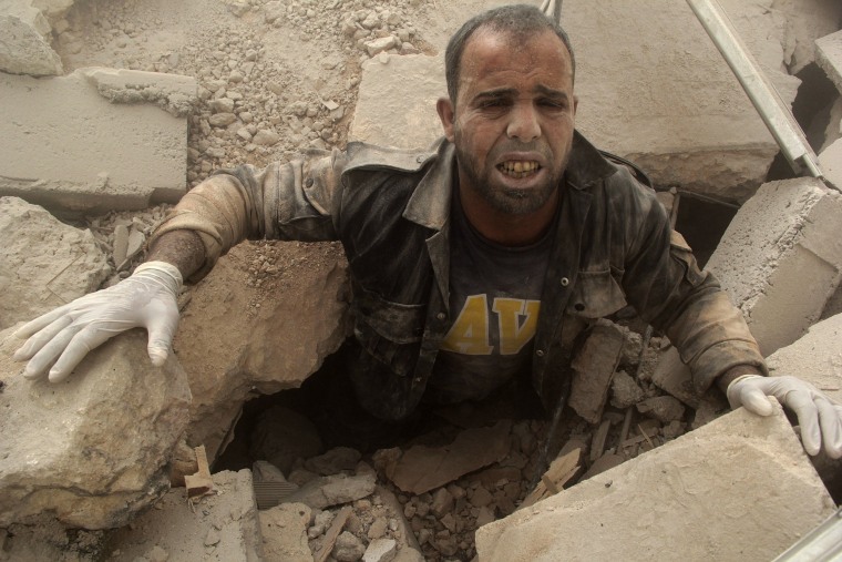 Image: A civil defence member is stuck under debris at a site hit by what activists said were two barrel bombs dropped by forces loyal to Syria's President Bashar al-Assad inAl-Shaar neighbourhood of Aleppo