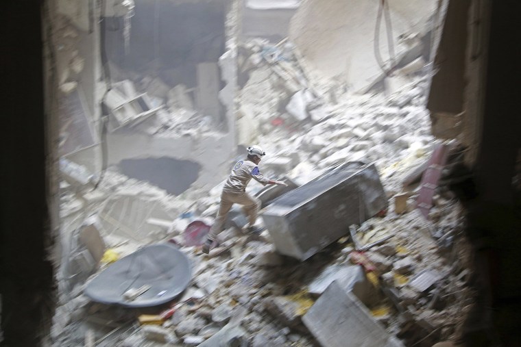 Image: A Civil defence member looks for survivors at a site hit by what activists said were two barrel bombs dropped by forces loyal to Syria's President Bashar al-Assad in the Al-Shaar neighbourhood of Aleppo J