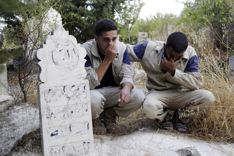 Image: Civil defense members mourn the death of their comrade, who died during what activists said were airstrikes carried out by the Russian air force, during his funeral in Ehsim town