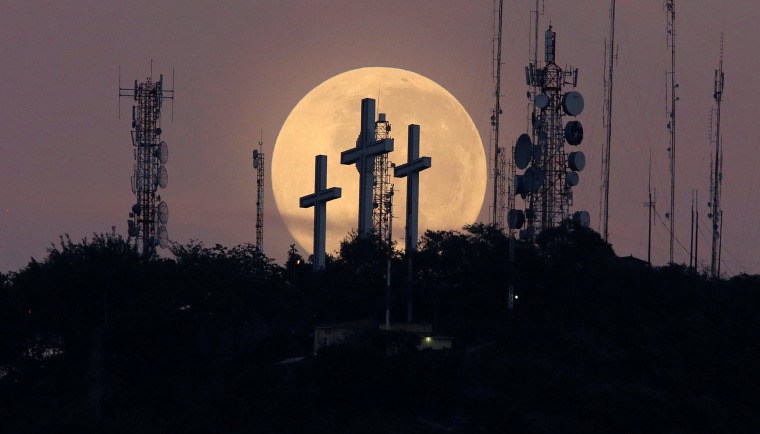 Image: The full moon is seen behind the hill of the three crosses in Cali