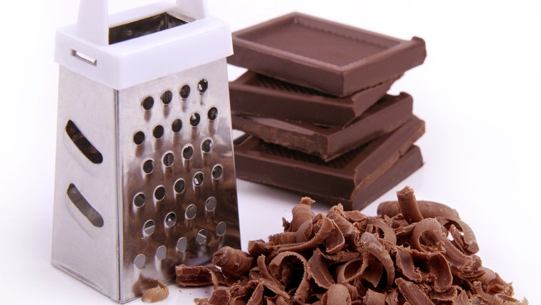 Grater, chocolate pieces and chips on a white background