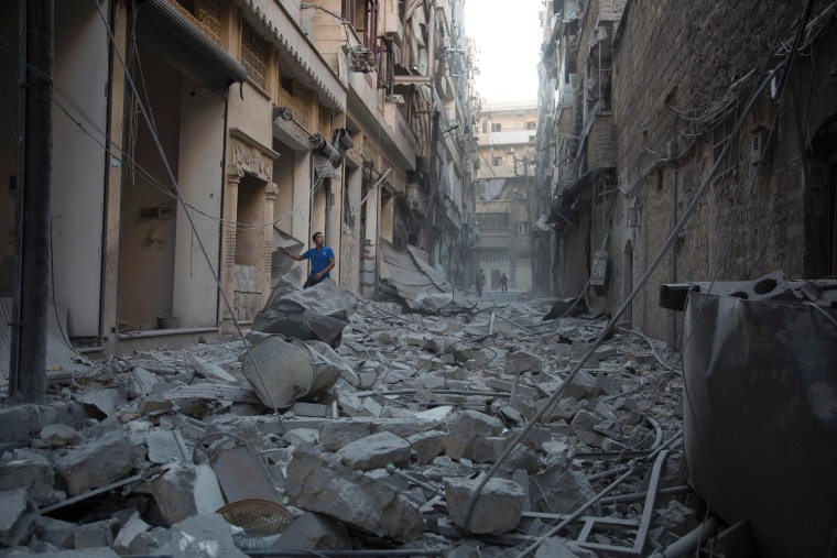 Image: A man stands in rubble in Aleppo