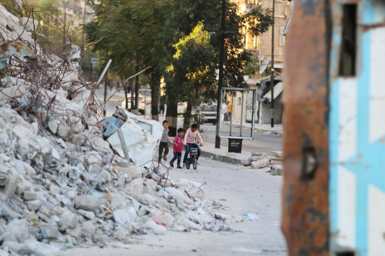 Image: Children play with a bicycle in Aleppo's rebel-held Bab al-Hadid neighborhood