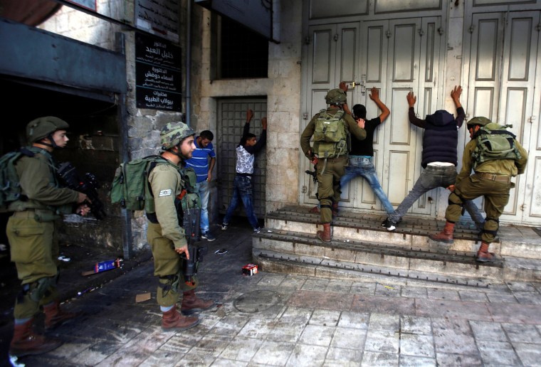 Image: Israeli soldiers search Palestinians during clashes in the West Bank city of Hebron