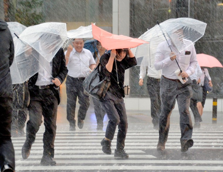 Image: Pedestrians holding umbrellas struggle against strong wind and heavy rains caused by Typhoon Malakas in Nagoya, central Japan