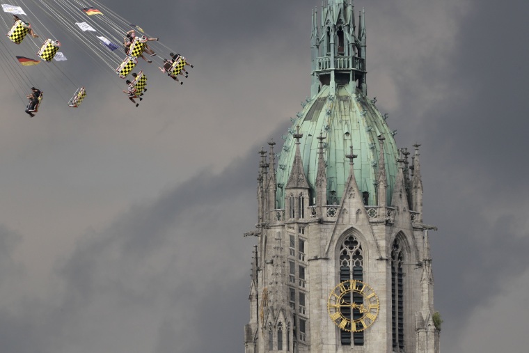 Image: People ride a swing in front of the St. Paul's church at the 183rd Oktoberfest beer festival in Munich
