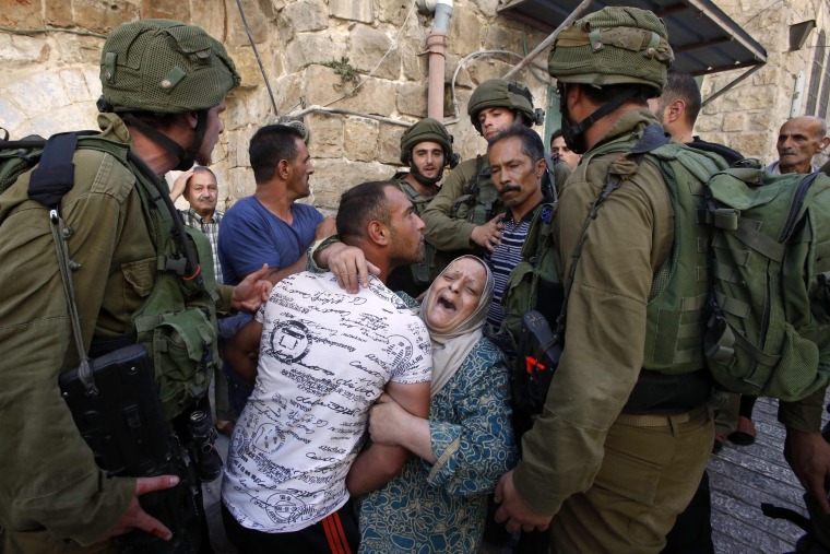 Image: A Palestinian woman tries to prevent the arrest of a Palestinian man by Israeli soldiers in the flashpoint city of Hebron