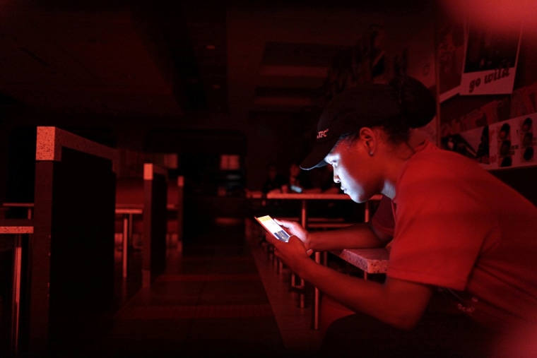 Image: An employee at a fast-food restaurant in a shopping mall uses her mobile phone during a power outage that affected several areas in the country, in San Juan