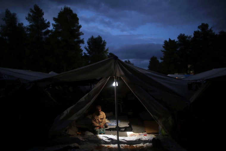 Image: A Syrian man sits inside his tents at Ritsona refugee camp north of Athens