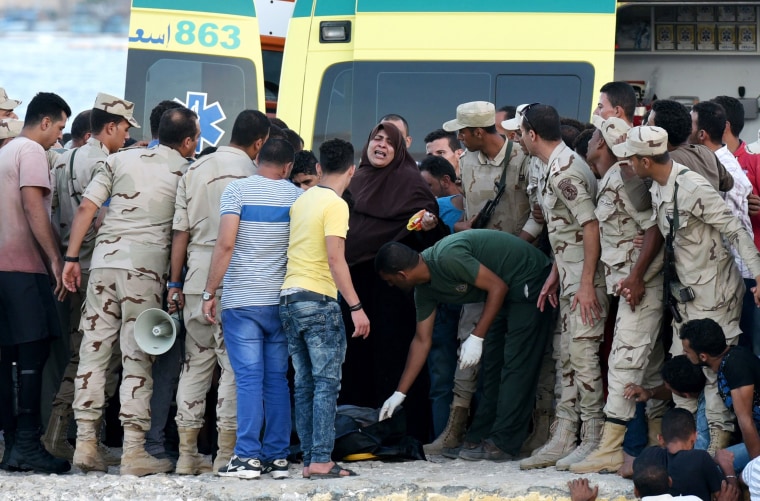 Image: Egyptian policemen and medics stand over a body of a migrant along the shore in the Egyptian port city of Rosetta