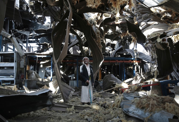 Image: An elderly man stands among the rubble of the Alsonidar Group's water pump and pipe factory