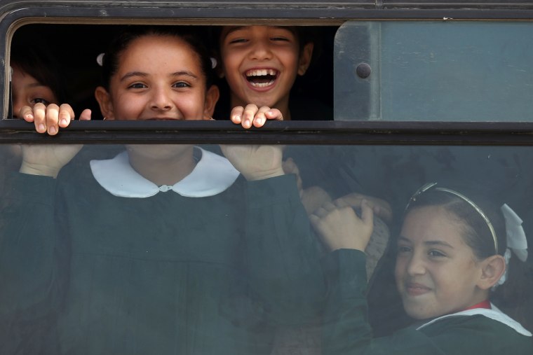 Image: Palestinian school girls smile to the camera as they come back home in their school bus
