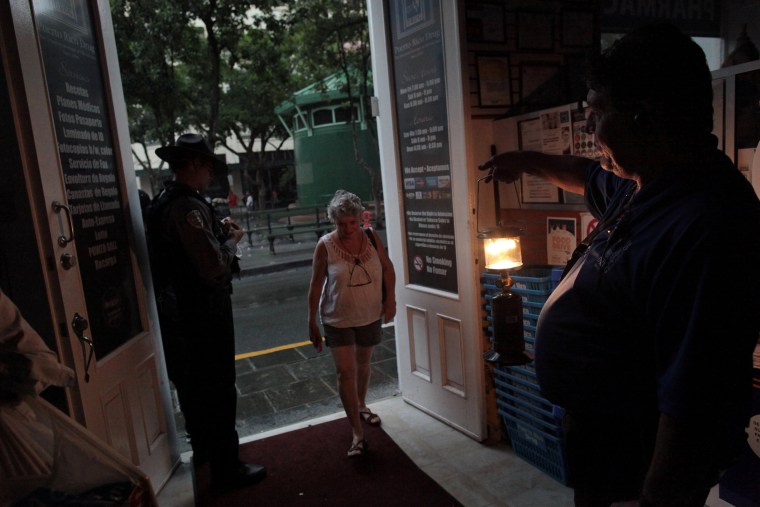 Image: A client enters a drugstore during a power outage after a fire at an energy plant knocked out electricity for the bulk of the island, in San Juan
