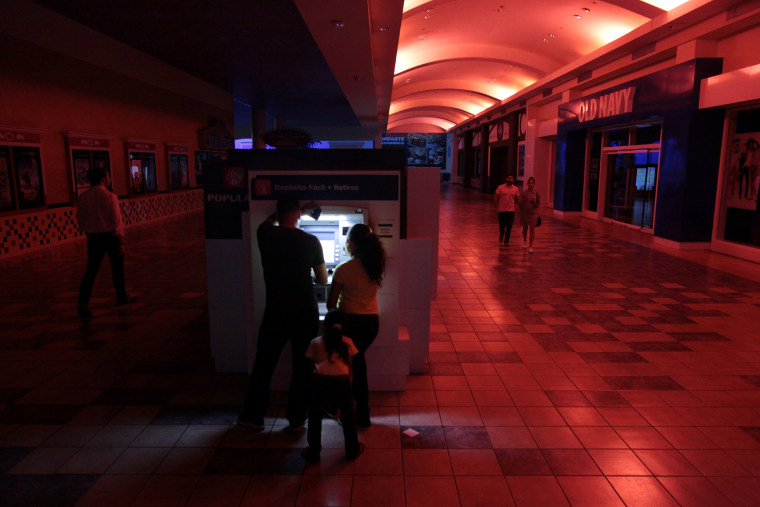 Image: People use an ATM machine at a shopping mall during a power outage that affected several areas in the country, in San Juan