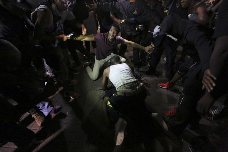 Image: A young man is attended to as he lies on the sidewalk after being shot in front of the Omni Hotel in downtown Charlotte, N.C.