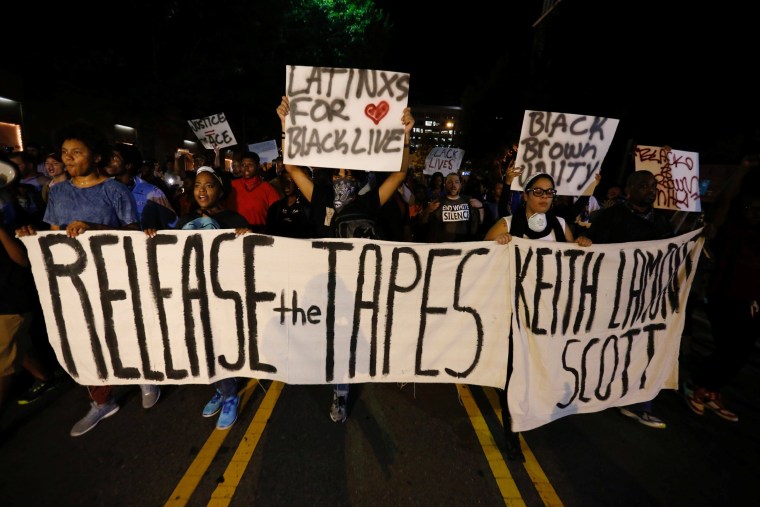 Image: Protesters hold signs while marching to demonstrate against the police shooting of Keith Scott in Charlotte