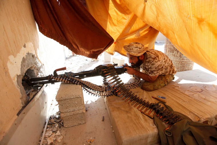 Image: Fighter from Libyan forces allied with the U.N.-backed government aims his weapon as he takes a position on a building rooftop during a battle with Islamic State militants in Sirte