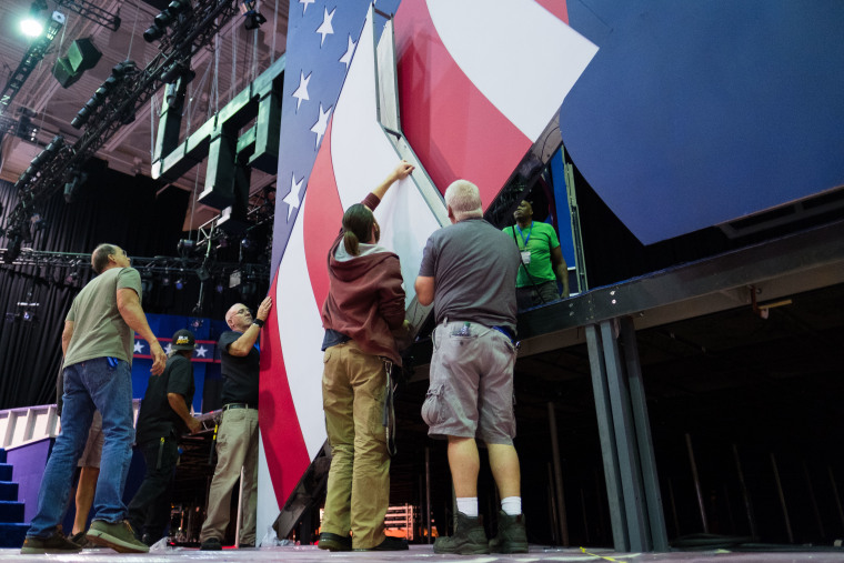 Construction crews hang part of the set as preparations continue for the Monday, Sept. 26, 2016, presidential debate between Democratic Hillary Clinton and Republican Donald Trump. 