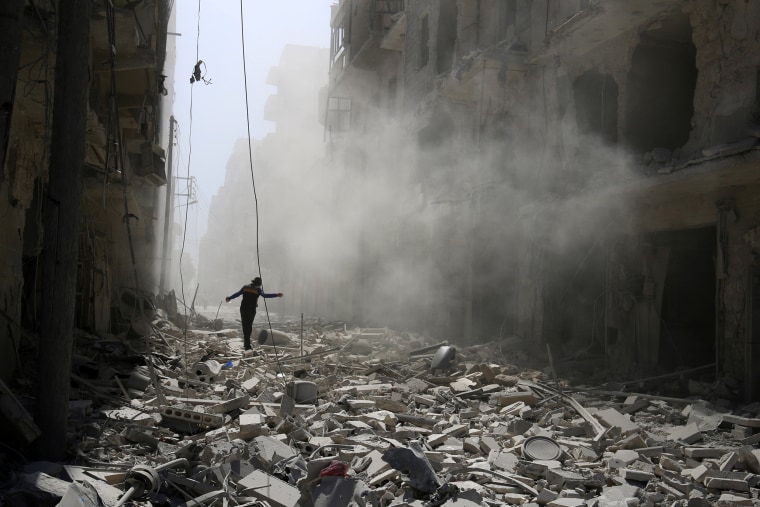 Image: A man walks on the rubble of damaged buildings after an airstrike on the rebel held al-Qaterji neighbourhood of Aleppo