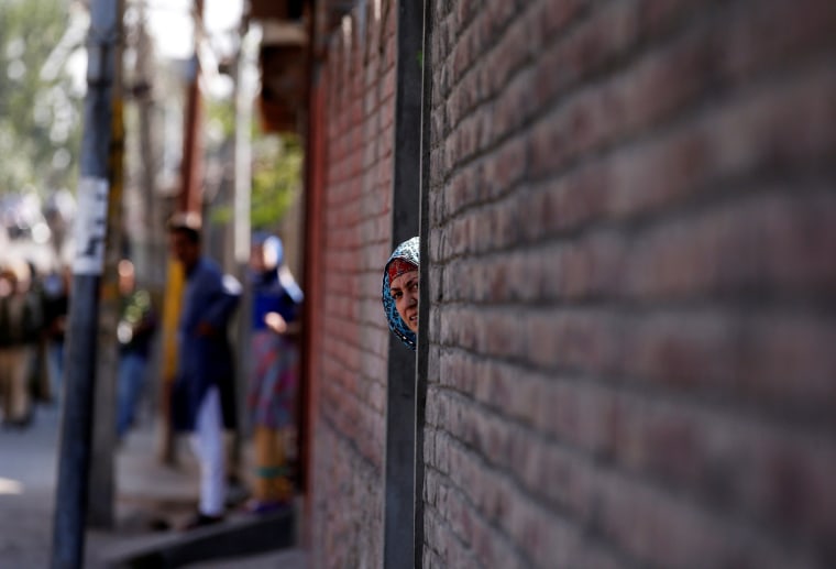 Image: A woman looks out from a door during a protest in Srinagar, against the recent killings in Kashmir region