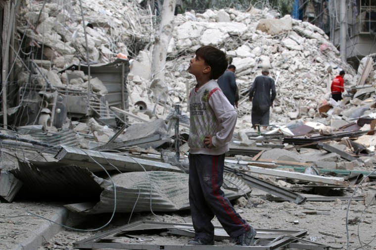 Image: A boy inspects a damaged site after airstrikes on the rebel held Tariq al-Bab neighbourhood of Aleppo