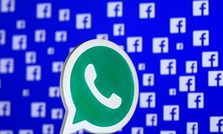 A 3D printed Whatsapp  logo is seen in front of a displayed Facebook logo in this illustration taken