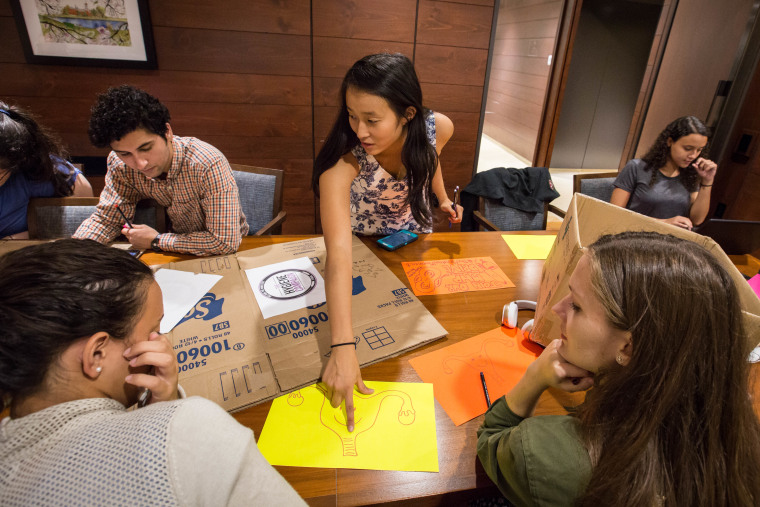 Okamoto points to a drawing of a smiling uterus at the Harvard Hygiene Campaign club meeting as students prepare for a drive to collect tampons and pads for homeless women in Boston.