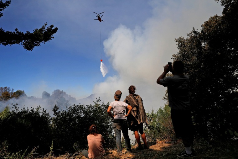 Image: A group of residents who remained despite the mandatory evacuation watch a firefighting helicopter make a drop near their properties along Summit road during the Loma Fire near Santa Cruz, California