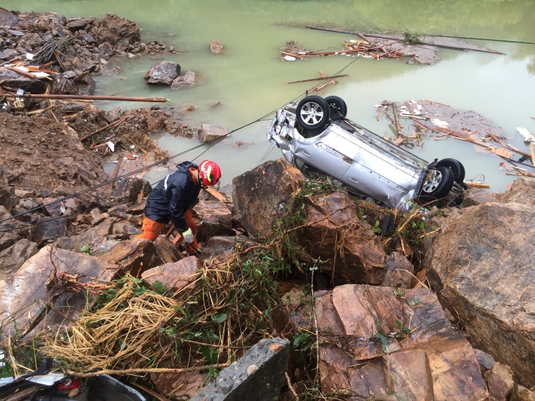 Image: A rescue worker is seen next to an overturned car at the site of a landslide caused by heavy rains brought by Typhoon Megi, in Sucun Village, Lishui